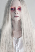 Young woman with spooky red eyes and long hair against white background