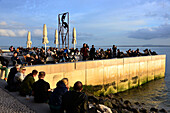 People sitting on the banks of the river Tejo at Cais do Sodre, Lisbon, Portugal