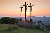 Participants of pilgrimage from Würzburg enjoy a picnic near summit cross on Kreuzberg mountain at sunset