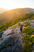 A woman hiking at sunset on Grassy Ridge while backpacking on the Roan Highlands near  Bakersville, North Carolina.