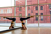 Weibliche Yogalehrerin im Kopfstand mit Hechtbeinen im Yogastudio in Baltimore, Maryland
