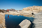 Reflection of a hiker in a glacier fed alpine tarn near Whistler, British Columbia, Canada.