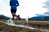 Trail runner splashing through a puddle.