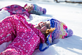 Young girls smiling and playing in the snow on a beautiful winter day.