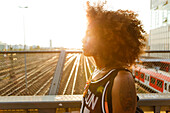 Young afro-american woman in backlight in urban scenery with tracks and station, Hackerbruecke Munich, Bavaria, Germany