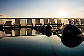 Pool with stop rope and deck chairs in the background against the light of the sunrise, Daytona Beach, Florida, USA