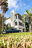 A vintage black Cadillac in front of a typical Florida residence with palm trees, Miami Beach, Miami, Florida, USA