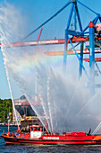 A fire-fighting boat of the fire brigade greets for the harbour birthday with fountain at the container terminal Burchardkai, Hamburg, Germany