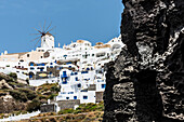 View at the steep coast and the village with the windmill and the traditionally built houses, Oia, Cyclades, Santorini, Greece