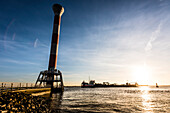 ' A dredger passes the lighthouse  ''Unterfeuer Blankenese'' (42 m high) at sunset, Blankenese, Hamburg, Germany'