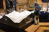 A small group plans backcountry routes on 3D mountain model inside visitor center