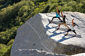 Three people do yoga on a rock platform in Little Cottonwood Canyon, Utah.