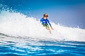 Young surfer, happy young boy in the ocean on surfboard