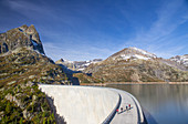 Four road bikers on the dam of the Emosson reservoir lake in the Alps on the border of France and Switzerland. It is an early morning training session of the local cyclists. The climb from Martigny to Finhaut will be stage 17 of the 2016 Tour de France on