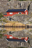 Schwedenhaus mit Spiegelung am Meer im Schärengarten, Insel Koö, Bohuslän, Västergötland, Götaland, Västra Götalands län, Südschweden, Schweden, Nordeuropa, Europa