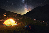 Two hikers watch the starry sky and milky way, camping spot in the Pfunderer Mountains, South Tyrol, Italy