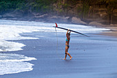 Young woman with surfboard on a beach.