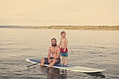 Caucasian father and son on paddleboard in lake