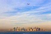 Jet airplane after take off from Hamad International Airport, seen above Doha city skyline from the sea, Qatar, Middle East