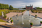 Blick über den Barockgarten mit Springbrunnen auf das Wasserschloss Frederiksborg an einem Sommertag, Hillerød, Hovedstaden, Dänemark