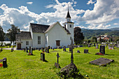 Ulvik church with blue sky, flowers and graves in the summer, Hardangerfjord, Hordaland, Norway, Scandinavia