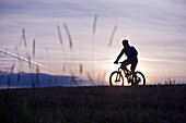 Young woman riding with her bike through a field