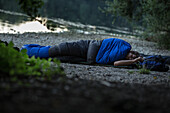 Junger Mann schläft draußen an einem See, Freilassing, Bayern, Deutschland
