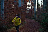 Young man running on a trail through a forest, Allgaeu, Bavaria, Germany