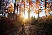 Young man running on a trail through a forest, Allgaeu, Bavaria, Germany