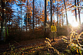 Young male runner standing on a trail in a forest, Allgaeu, Bavaria, Germany