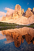 Three Peaks of Lavaredo, Sexten dolomites, Trentino-Alto Adige, Italy. The Three peaks of Lavaredo are reflected into the small lake at sunset, near Locatelli refuge