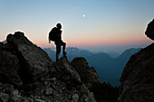 Europe, Italy, Veneto, Belluno, Dolomites. Silhouette of hiker in mountain at dusk