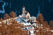The parish church of Colle Santa Lucia framed by autumn larches, Agordino, Dolomites