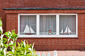 Zwei Segelschiffe und ein Leuchtturm als Modelle im Fenster eines typisches Friesischen Backsteinhauses, Juist, Schleswig Holstein, Deutschland