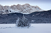 Baumbestandene Insel im zugefrorenen Eibsee, Blick zur Zugspitze, bei Grainau, Bayern, Deutschland