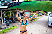 Young woman is preparing surfboard before surf session.