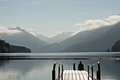 A woman sits on the end of a dock overlooking Lake Crescent in Olympic National Park, Washington on June 4, 2014.
