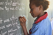 Young girl completing a gap filling exercise on a chalkboard at Malasang Primary School, Buka, Bougainville, Papua New Guinea, Pacific