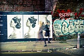 unrecognizable people in mouvement, walking below a bridge with graffiti and advertising on the walls. Shoreditch, East London, London, England, UK, Europe