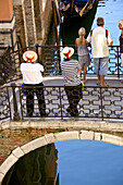 Two gondoliers on a bridge waiting for tourists, with a gondola, Venice, Italy.