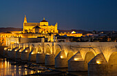Córdoba´s Puente Romano, spanning the Guadalquivir river, and the Mezquita in the background. Illuminated at dusk. Córdoba, Córdoba province, Andalusia, Spain.