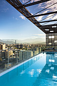 Chile, Santiago, elevated city view towards the Gran Torre Santiago tower from high rise building swimming pool, dawn.