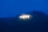 Romania, Transylvania, Brasov, Mt. Tampa, illuminated Brasov sign, dusk.