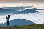 Germany, Baden-Wurttemburg, Black Forest, Belchen Mountain, summit view towards the Vosges Mountains in France with autumn fog and people.