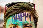 Partial view of a young woman with the word happy on her face.