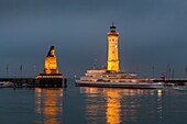The famous harbor entrance with lighthouse and Bavarian Lion sculpture at night in Lindau, Bavaria, Germany, Europe