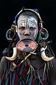 Portrait of woman of the Mursi tribe traditionally decorated and painted, wearing a large clay lipplate, Omo Valley, Ethiopia, Africa.
