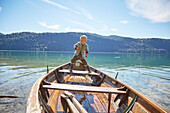 Junge balanciert auf Holzboot am See