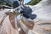 Junge Wanderin geht auf Felsen ziwschen einem Fluss, Val Verzasca, Tessin, Schweiz