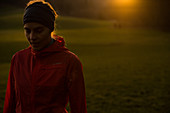 Junge Läuferin steht auf einem Feld bei einem Sonnenuntergang, Allgäu, Bayern, Deutschland